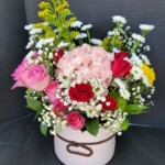 A bouquet of flowers in a white container.