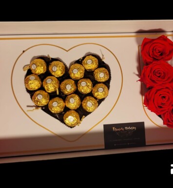 A box of chocolates and roses in the shape of a heart.