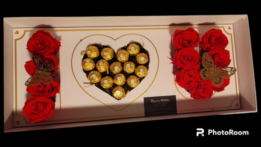 A box of chocolates and roses in the shape of a heart.