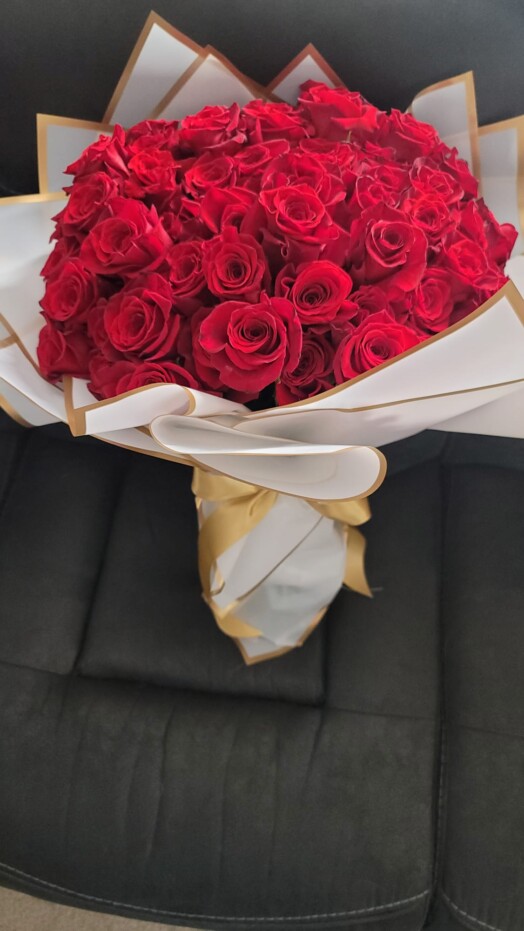 A bouquet of red roses wrapped in white paper.
