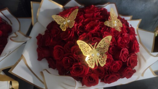 A bouquet of red roses with gold butterflies.