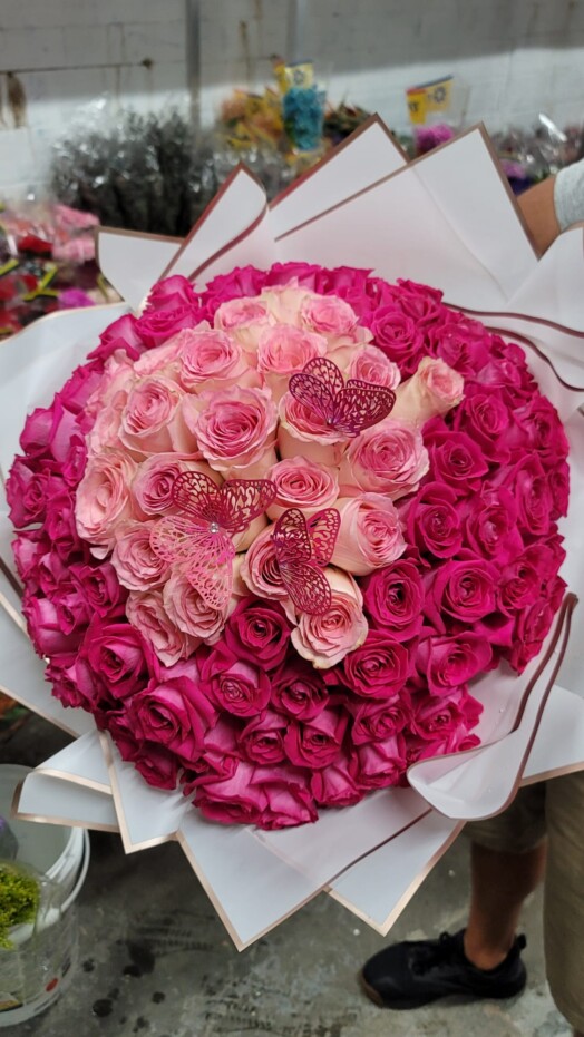 A bouquet of pink roses with hearts on it.